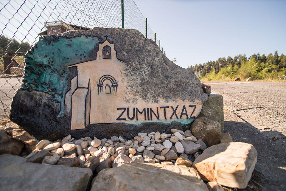 Señal con el logo pintado de Agroturismo Zumintxaz, que indica el camino para llegar al alojamiento.