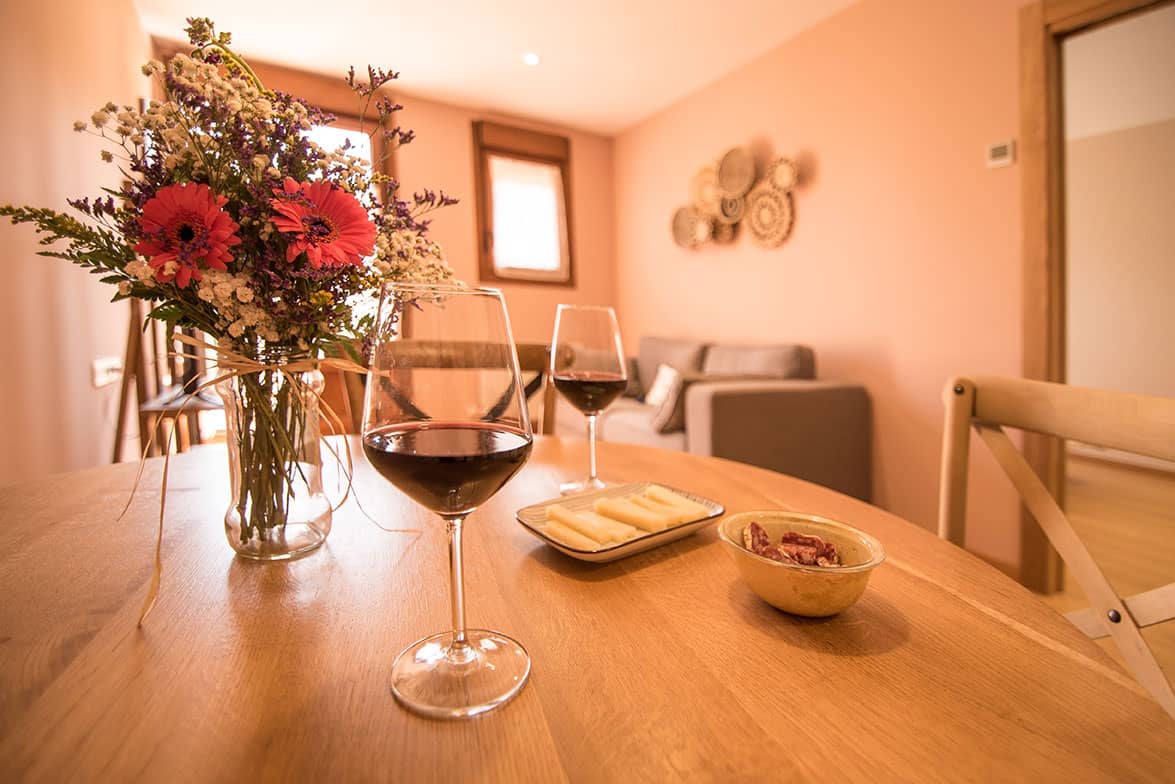 Detalle de la mesa del salón comedor, con copas de vino y un aperitivo, en uno de los apartamentos de agroturismo Zumintxaz